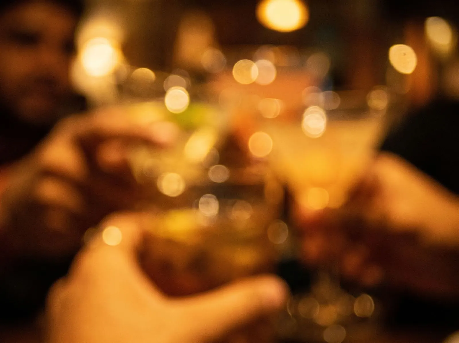 Warm bokeh and wine glasses, dim restaurant